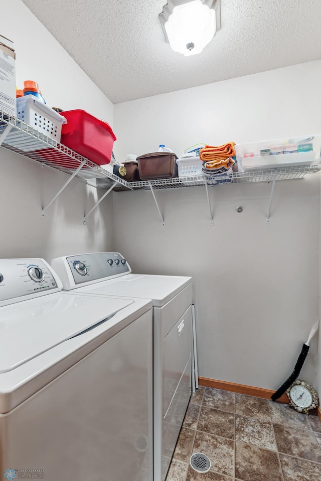 clothes washing area featuring a textured ceiling, washing machine and clothes dryer, and tile patterned floors