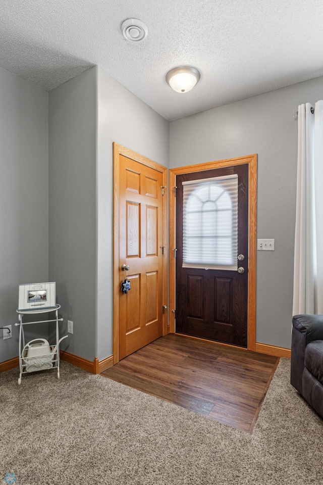 foyer entrance featuring a textured ceiling and dark hardwood / wood-style floors