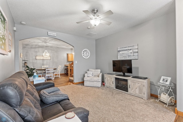 living room featuring ceiling fan, light colored carpet, and a textured ceiling