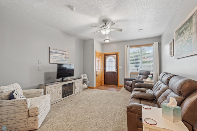 carpeted living room with ceiling fan and a textured ceiling