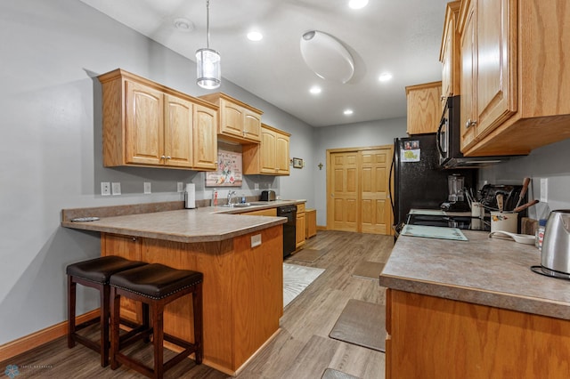 kitchen with a kitchen breakfast bar, decorative light fixtures, light hardwood / wood-style floors, dishwasher, and kitchen peninsula