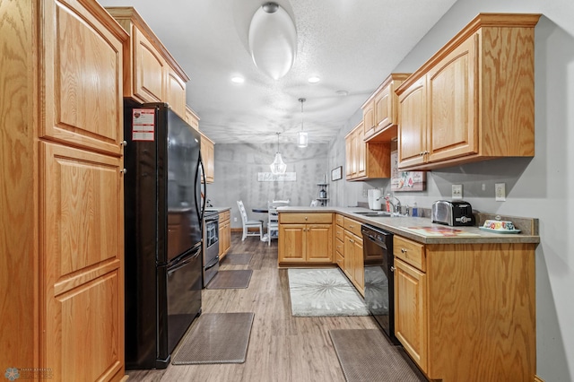 kitchen with light hardwood / wood-style floors, sink, black appliances, kitchen peninsula, and hanging light fixtures