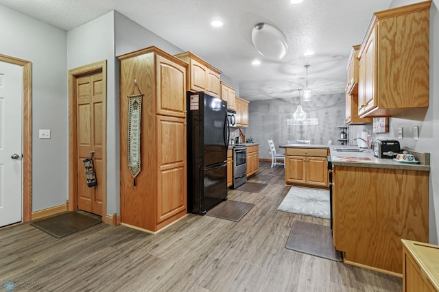 kitchen with light hardwood / wood-style floors, black refrigerator, range, and sink