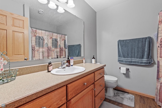 bathroom featuring wood-type flooring, toilet, a textured ceiling, and vanity