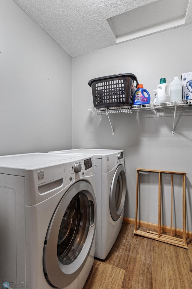 laundry room featuring a textured ceiling, hardwood / wood-style flooring, and separate washer and dryer