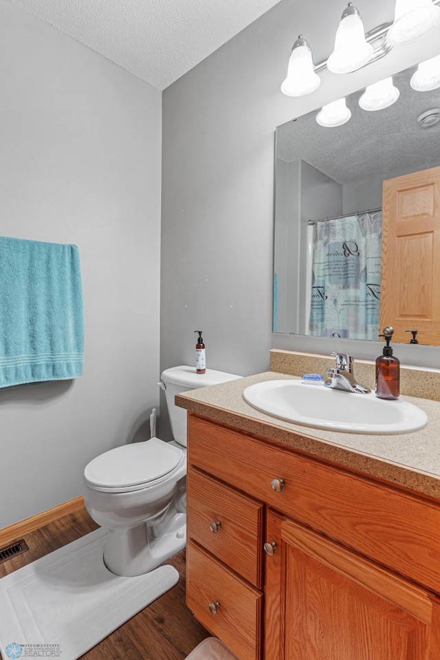 bathroom with hardwood / wood-style floors, toilet, a textured ceiling, and vanity