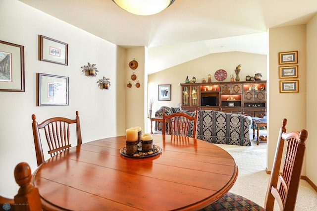 carpeted dining room featuring lofted ceiling