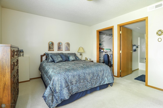 bedroom with a closet, a spacious closet, light colored carpet, and a textured ceiling