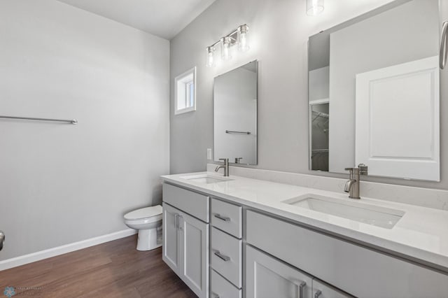 bathroom with hardwood / wood-style floors, dual vanity, and toilet