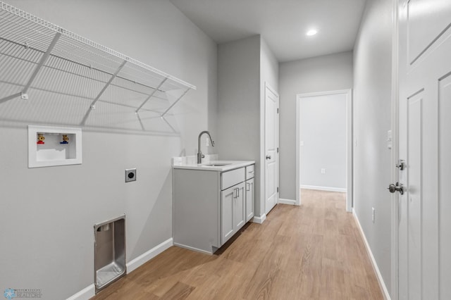 clothes washing area with sink, light hardwood / wood-style floors, electric dryer hookup, and hookup for a washing machine