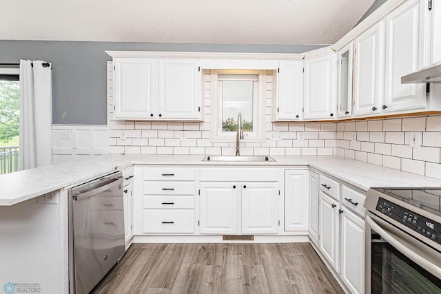 kitchen featuring backsplash, light hardwood / wood-style floors, stainless steel dishwasher, sink, and white cabinets