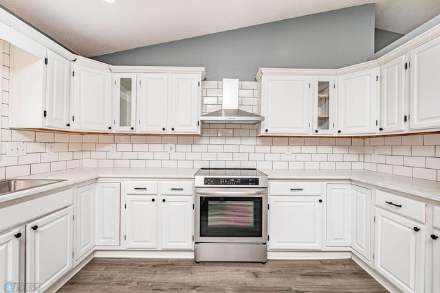 kitchen with decorative backsplash, wall chimney exhaust hood, electric stove, white cabinets, and wood-type flooring