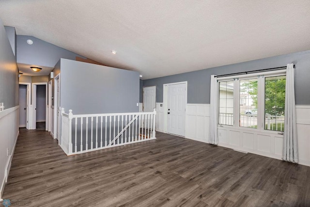 spare room featuring a textured ceiling, lofted ceiling, and dark wood-type flooring