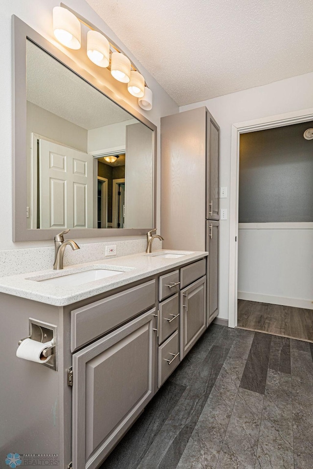 bathroom featuring a textured ceiling, dual vanity, and tile patterned floors