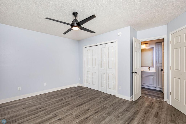 unfurnished bedroom featuring ceiling fan, a closet, a textured ceiling, and dark hardwood / wood-style flooring