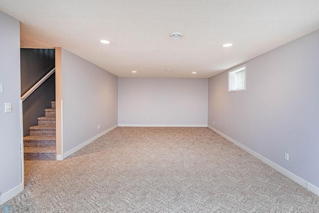 basement featuring light colored carpet and a textured ceiling