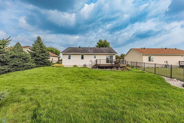 back of property featuring a wooden deck and a lawn