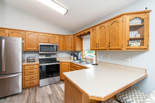 kitchen with stainless steel appliances, sink, light wood-type flooring, lofted ceiling, and kitchen peninsula