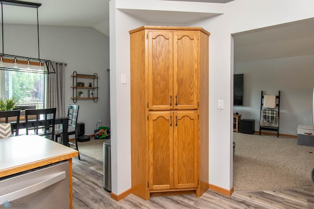 kitchen featuring dishwasher, light hardwood / wood-style floors, decorative light fixtures, and vaulted ceiling