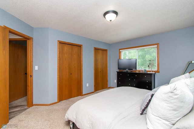 carpeted bedroom with two closets and a textured ceiling