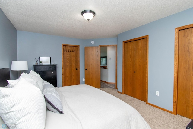 bedroom featuring carpet, two closets, and a textured ceiling