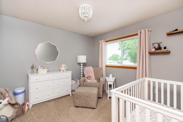 carpeted bedroom with a textured ceiling and a nursery area