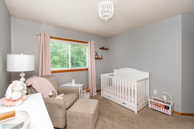 bedroom featuring a textured ceiling, a nursery area, and light colored carpet