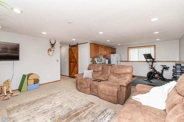 living room with a textured ceiling, light colored carpet, and a barn door