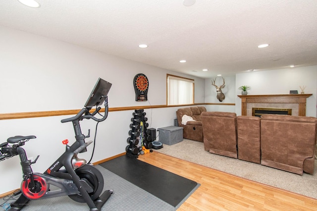 exercise room featuring a textured ceiling, a tiled fireplace, and hardwood / wood-style floors