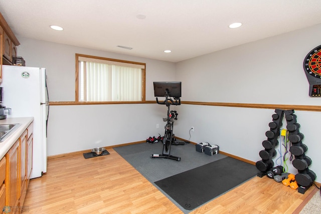 exercise room with light wood-type flooring