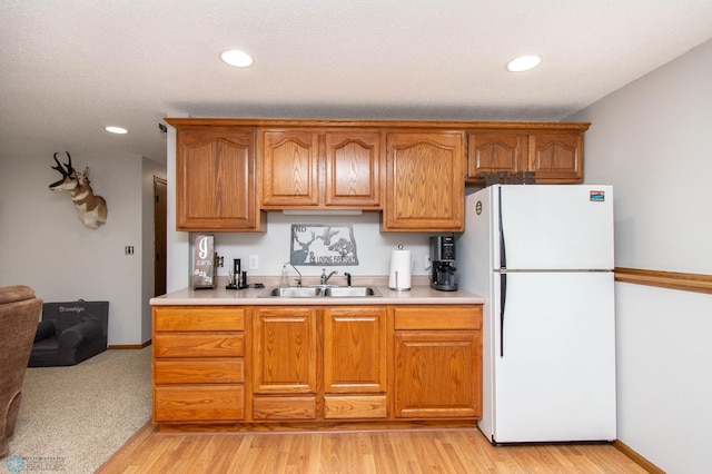 kitchen featuring light hardwood / wood-style floors, sink, and white fridge