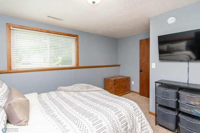 bedroom with light colored carpet and a textured ceiling