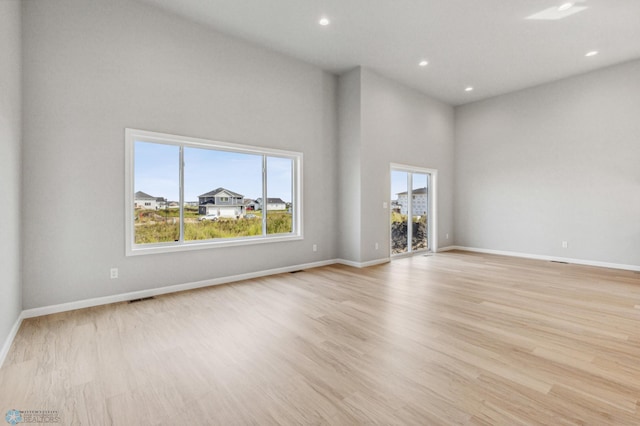 unfurnished living room with light hardwood / wood-style flooring and a towering ceiling