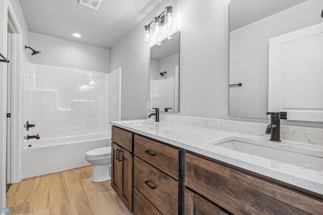 full bathroom featuring hardwood / wood-style floors, shower / bathing tub combination, toilet, and dual bowl vanity