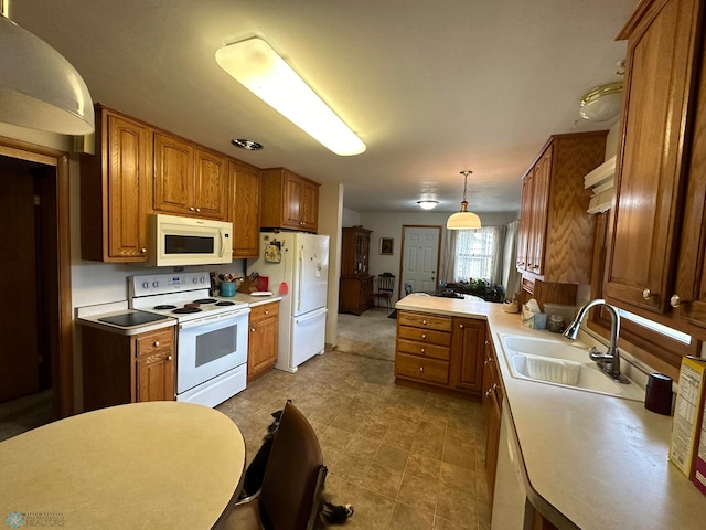 kitchen featuring white appliances, pendant lighting, kitchen peninsula, and sink