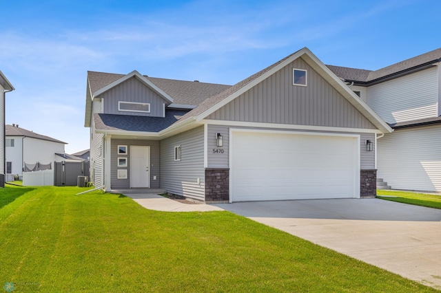 craftsman-style home with a garage, central air condition unit, and a front lawn