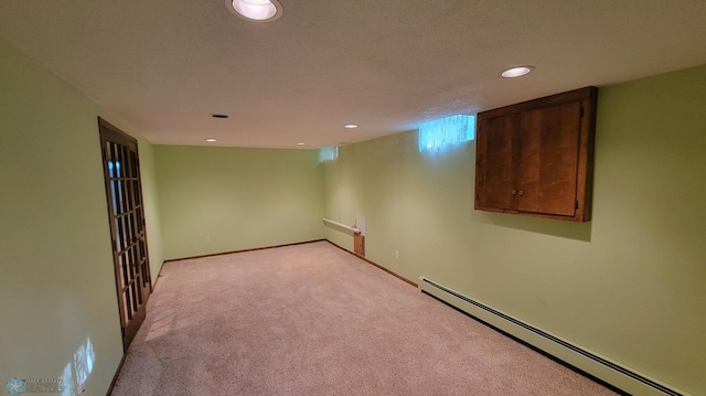 carpeted empty room featuring a baseboard radiator and a textured ceiling