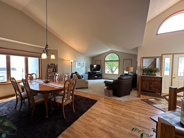 dining space featuring an inviting chandelier, hardwood / wood-style floors, and high vaulted ceiling