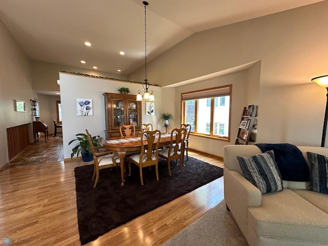 dining area with high vaulted ceiling, hardwood / wood-style floors, and a notable chandelier