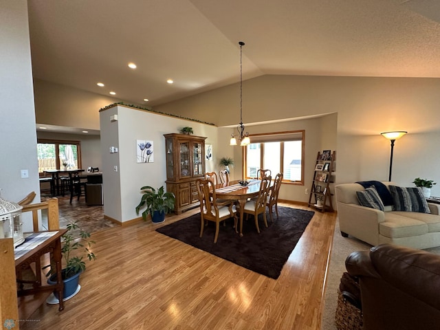 dining space with high vaulted ceiling, hardwood / wood-style flooring, and a chandelier