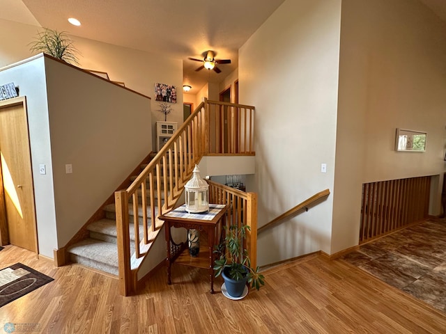 stairs featuring hardwood / wood-style floors and ceiling fan