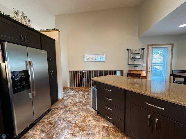 kitchen with light stone counters, light tile patterned flooring, and stainless steel refrigerator with ice dispenser