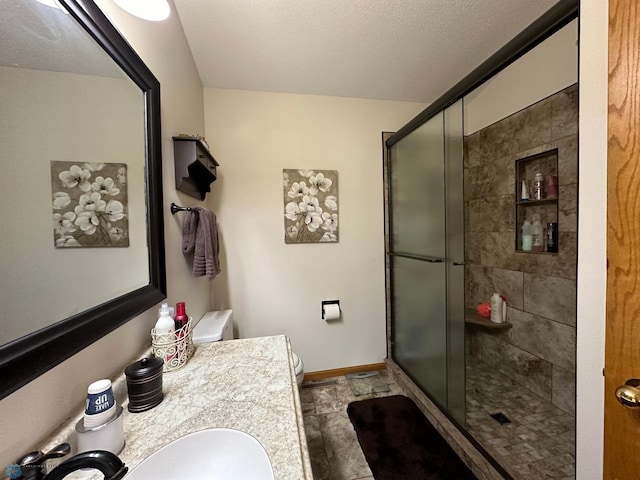 bathroom featuring a textured ceiling, tile patterned floors, toilet, a shower with shower door, and vanity