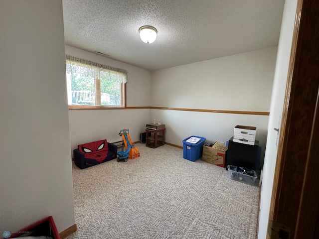 playroom featuring carpet flooring and a textured ceiling