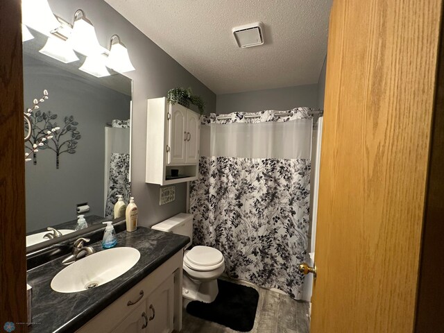 bathroom featuring walk in shower, toilet, a textured ceiling, and vanity