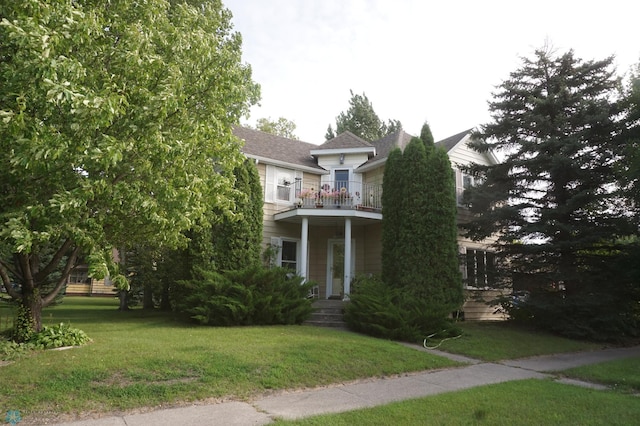 view of front of property featuring a balcony, a porch, and a front lawn