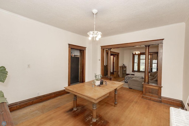 dining room with a textured ceiling, ornamental molding, an inviting chandelier, and light wood-type flooring