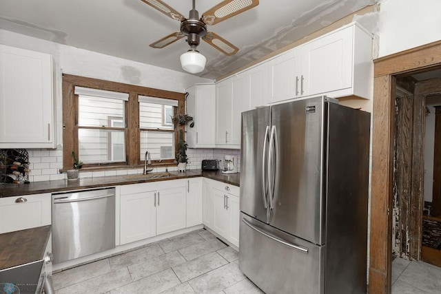 kitchen with appliances with stainless steel finishes, tasteful backsplash, sink, light tile patterned floors, and ceiling fan