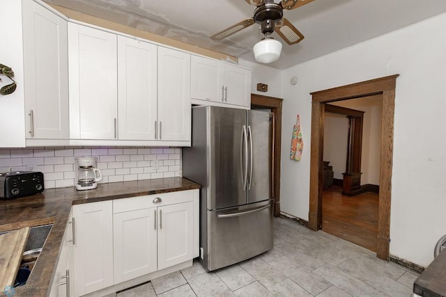 kitchen with backsplash, white cabinetry, light hardwood / wood-style floors, ceiling fan, and stainless steel fridge