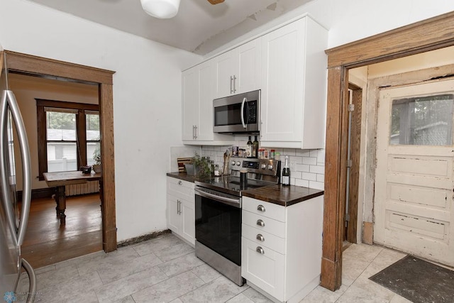 kitchen with light tile patterned floors, appliances with stainless steel finishes, decorative backsplash, and white cabinets